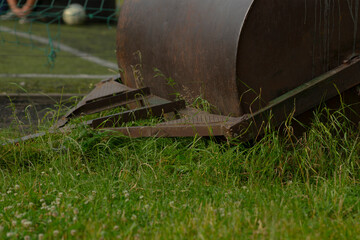 The image clearly depicts a grass cutting machine placed on a soccer field where the grass has grown excessively tall, suggesting that maintenance work is urgently required