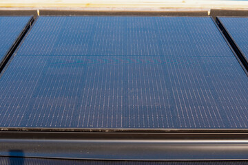 Close-up of Solar panels cover building's roof reflecting the sun's rays during daylight