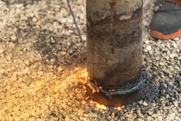 Close-up of cutting steel pipe with help of welding tool creating melted steel, sparks and fumes