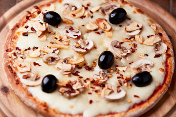 Pizza with champignons, black olives and mozzarella cheese. Wooden background. Soft focus.	