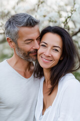 Obraz premium Caucasian mature couple embracing in nature with blossoming trees