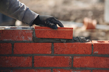 Close-up of skilled bricklayer working on construction site laying bricks for wall construction