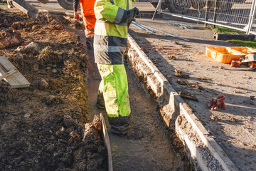 Builders pouring concrete footing next to road