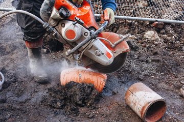 Builder cutting drainage pipe with petrol power steel saw