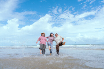 Friends enjoy a joyful day at the beach, splashing in the waves under a cloudy sky