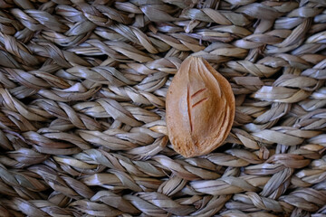 A single apricot pit with a carved rune rests on a textured straw mat. The minimalist composition...
