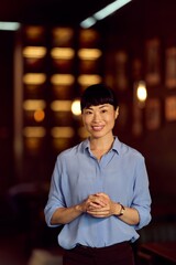 Smiling Woman in Elegant Attire Standing in a Warmly Lit Interior