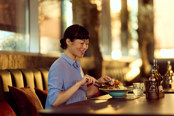 Woman Enjoying a Meal in a Well-Lit Cozy Restaurant Setting