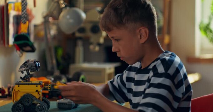 A boy enthusiastically builds a robot from a construction kit while sitting at a table at home