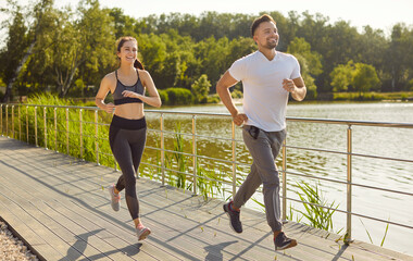 Sporty people man and woman running together along a bridge having sport jog workout outdoors....