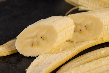 open banana on a slate board, ripe and sweet yellow banana on a kitchen board made of black stone
