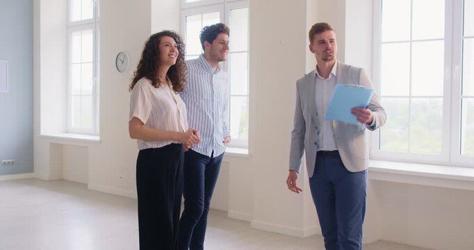 Real estate agent, realtor meets clients family couple standing in empty room apartament, new office moving, represent sellers, buyers, showing real property, consulting on relocation, interior design