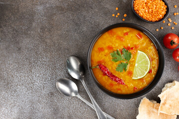 Indian dal soup with red lentils, spices, cilantro, lime on gray background. Indian food. Top view