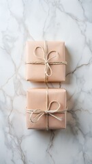 Two simple brown paper wrapped gifts tied with twine on a marble surface