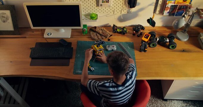 A view from behind of a boy who is making a robot