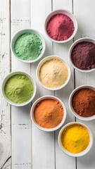 Colorful natural powders in small white bowls arranged on a white wooden surface