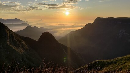 Majestic sunrise over a vast mountain range with golden light, misty valleys, and layered peaks....