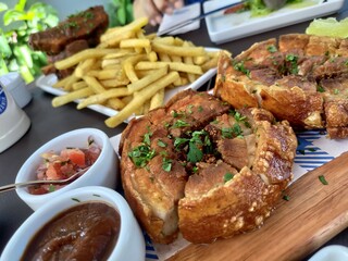 Crispy fried pork belly appetizer platter, garnished with fresh parsley and served on a wooden...
