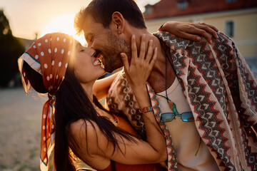 Carefree couple kissing during summer music festival at sunset.
