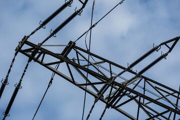 A close-up of a metal support for high-voltage power lines against a blue sky. Electricity supply,...