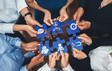 Diverse group of hands assembling puzzle pieces that symbolize collaboration, teamwork, and CRM...