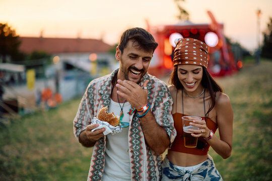 Happy couple enjoying in beer and burgers during summer music festival.