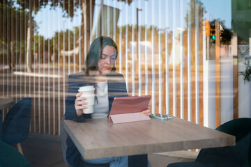 Businesswoman working on tablet and drinking coffee in cafe