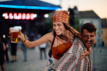 Cheerful couple having fun in front of music stage on summer festival.
