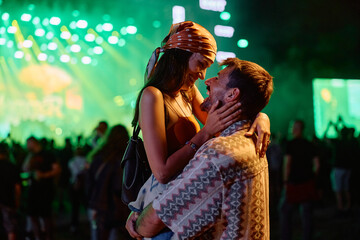 Affectionate couple in front of stage during summer music concert at night.