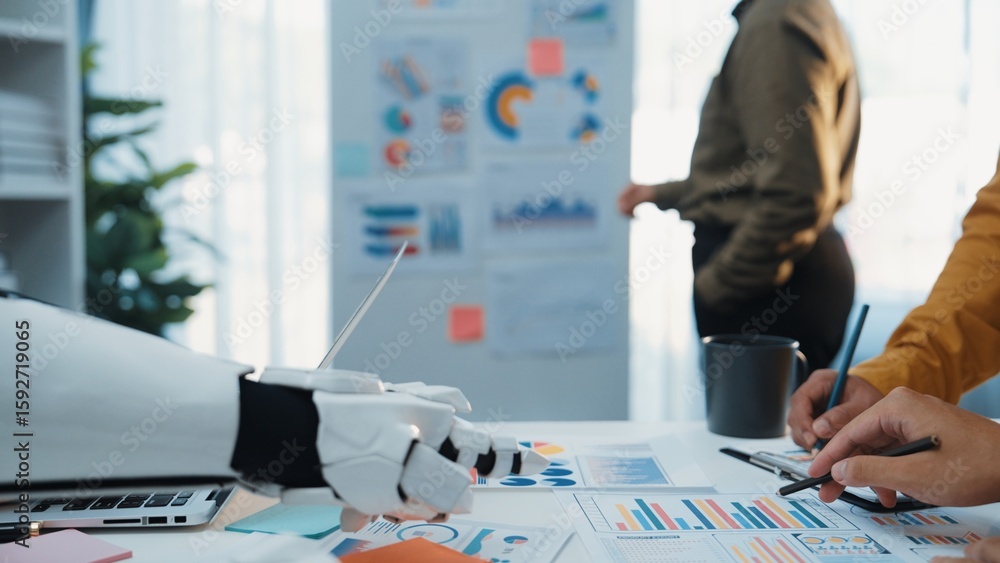 Poster a close-up view of a workspace featuring a robotic arm and human hands working on charts and graphs,