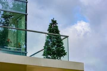 Modern glass balcony with a decorative Christmas tree, minimalist contemporary architecture with...