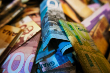 Vibrant colorful photo of mixed Ghanaian cedi notes currency money spread scattered on table desk ground floor surface background
