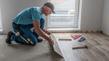 Floating floor work. The worker inserts the board of vinyl plank to the click system of Floating...