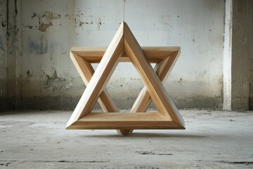 A wooden star of david stands in an empty room with a concrete floor
