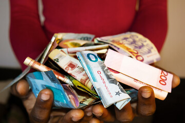 Person holding in open palm mixed Ghanaian cedi notes currency money