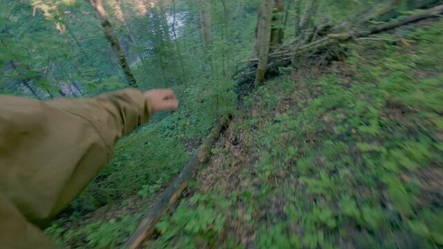 A man walks down a steep slope to the river. A traveler on a camping trip. From the first person.