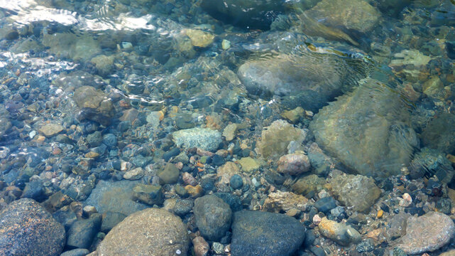 Fondo de piedras del rio con agua cristalina que forma olas