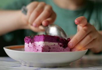 Close-Up of Child's Hands Actively Scooping Layers of Purple Berry Mousse Cake