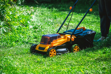 Gardener cutting overgrown grass with a lawn mower in a backyard garden on a sunny summer day, diligently maintaining the lush lawn and enhancing the outdoor space
