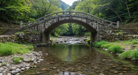 Fototapeta premium Historic stone arch bridge crossing a clear river in a beautiful and lush green forest