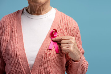 Senior woman showing pink ribbon for breast cancer awareness