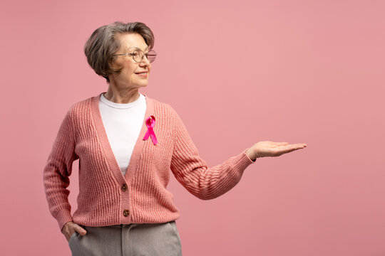 Senior woman showing something on her palm for breast cancer awareness - Powered by Adobe