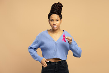 Smiling woman showing pink ribbon supporting breast cancer awareness month