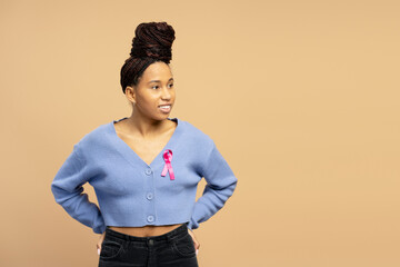 Young woman wearing pink ribbon looking aside supporting breast cancer awareness campaign