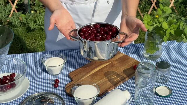 A person prepares fresh cherry jam outdoors, showcasing sustainable cooking, fresh ingredients, and rustic charm