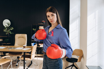 Businesswoman wearing boxing gloves and pink ribbon supporting breast cancer awareness