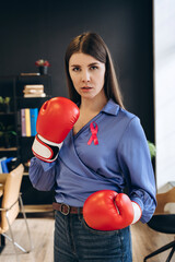 Businesswoman wearing boxing gloves and pink ribbon fighting against breast cancer