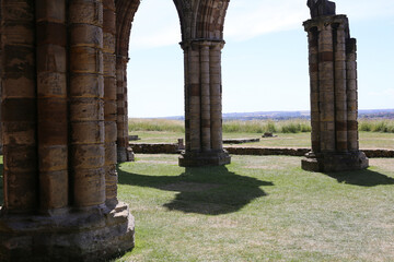 Fototapeta premium stone pillars standing in a field, likely part of an old building or ruins at Whitby Abbey - Whitby - North Yorkshire - Great Britain