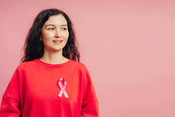 Woman wearing pink ribbon supporting breast cancer awareness looking away smiling