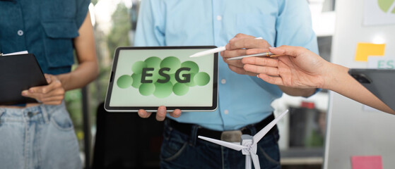 Sustainability focus. Team discussing ESG strategies with digital tools in a collaborative office.